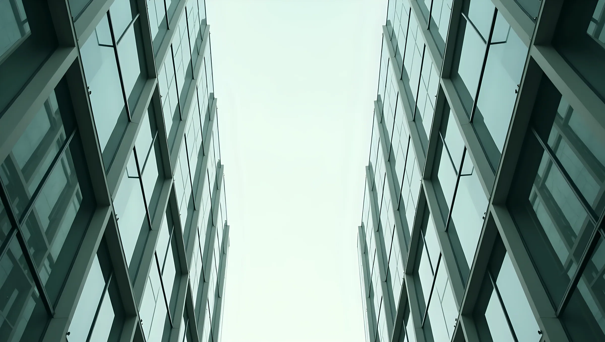 A desaturated, high-contrast photograph of glass and steel, close material texture, graded to the brand's forest and stone tones.