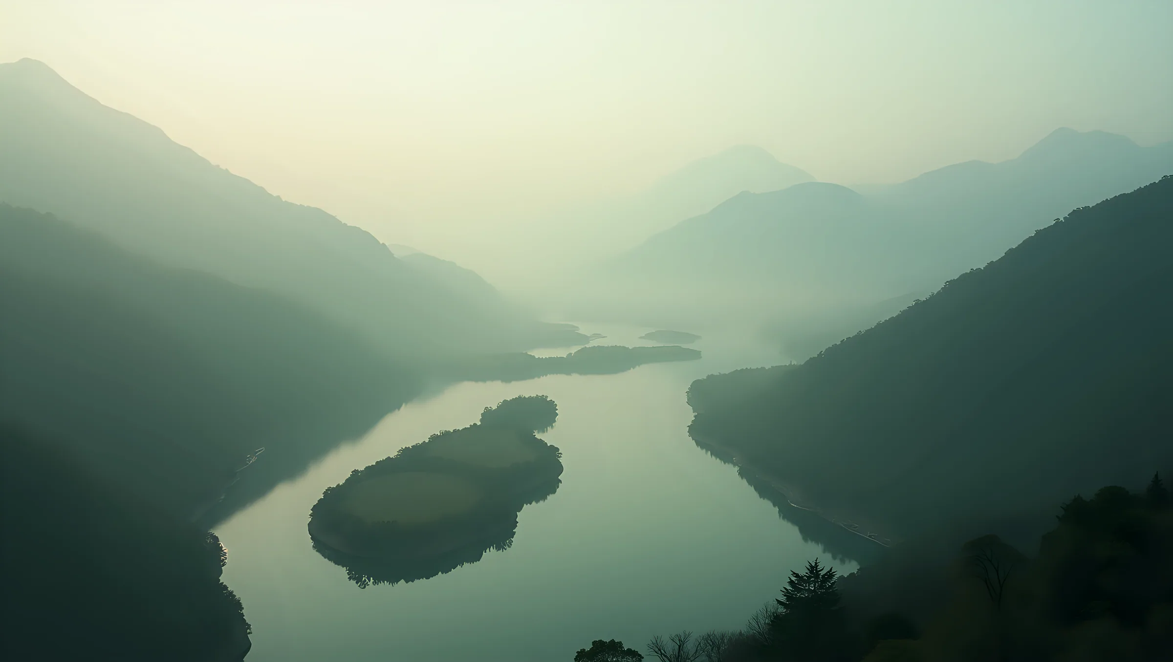 A desaturated, high-contrast photograph of a valley falling away beneath it, still water, graded to the brand's forest and stone tones.